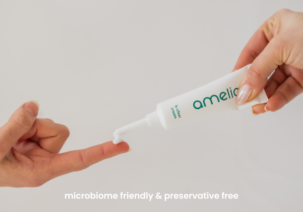 Tube of 'amelia' cream being applied to a hand with a plain background