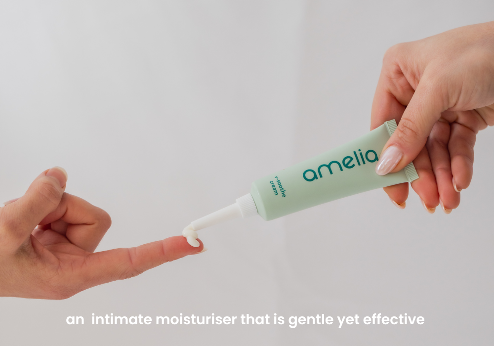Hand holding a tube of 'amelia' intimate moisturizer with text on a light gray background