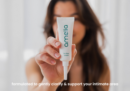 Person holding a tube of 'amelia' cream with a blurred background